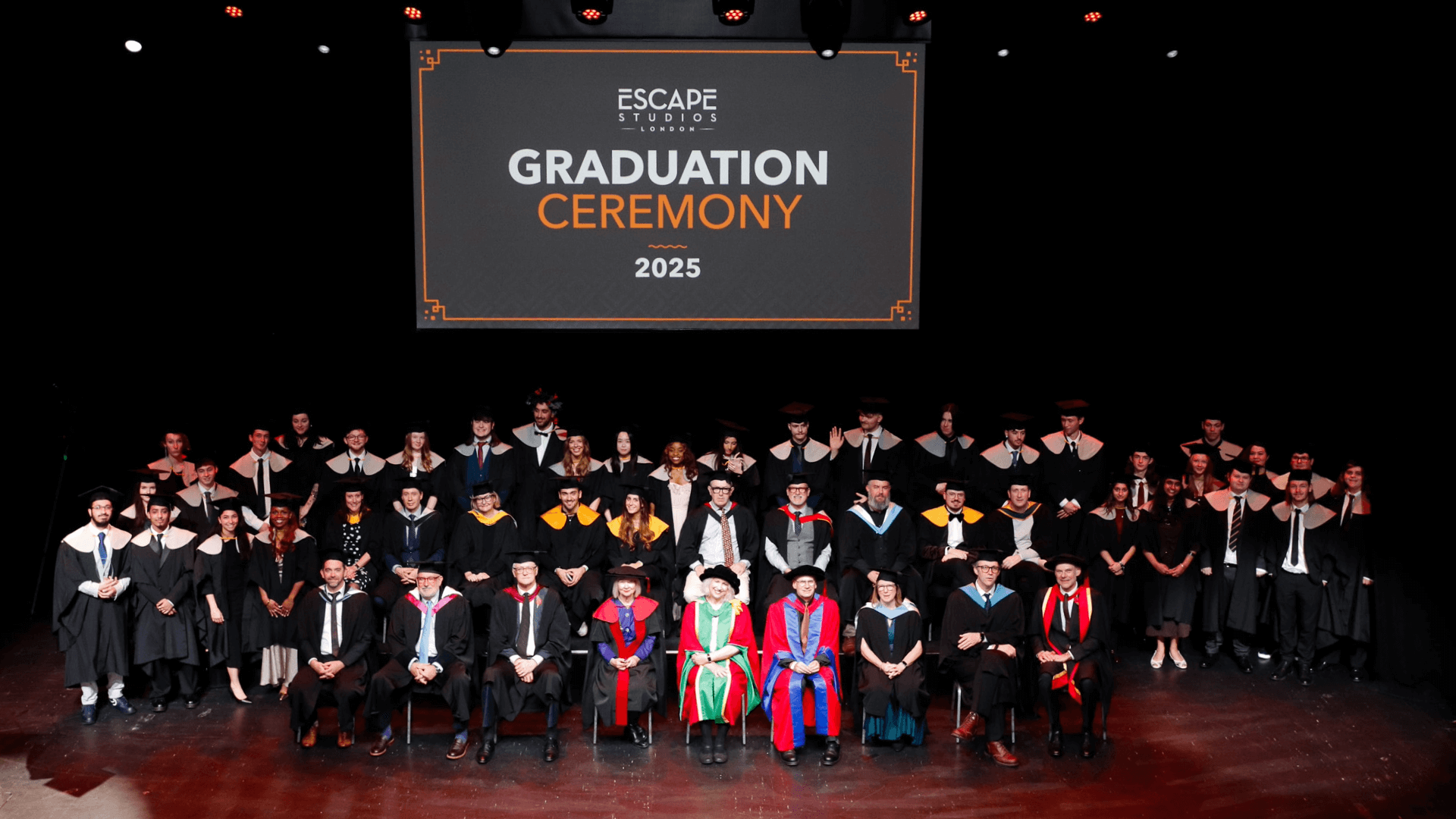 A group of staff and graduates posing on stage at the 2025 Escape Studios graduation ceremony