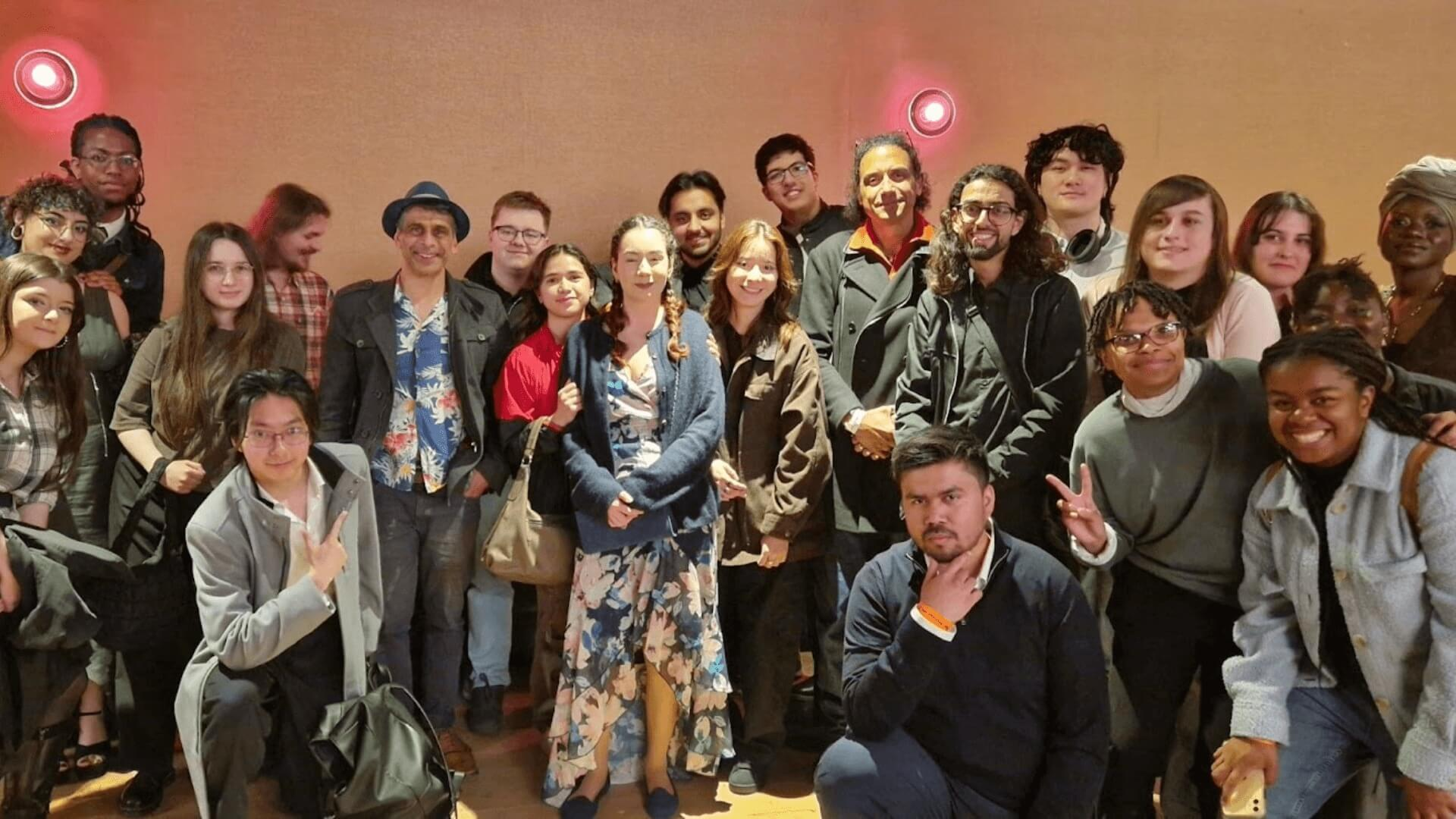 A large group of students posing for the camera against a plain wall