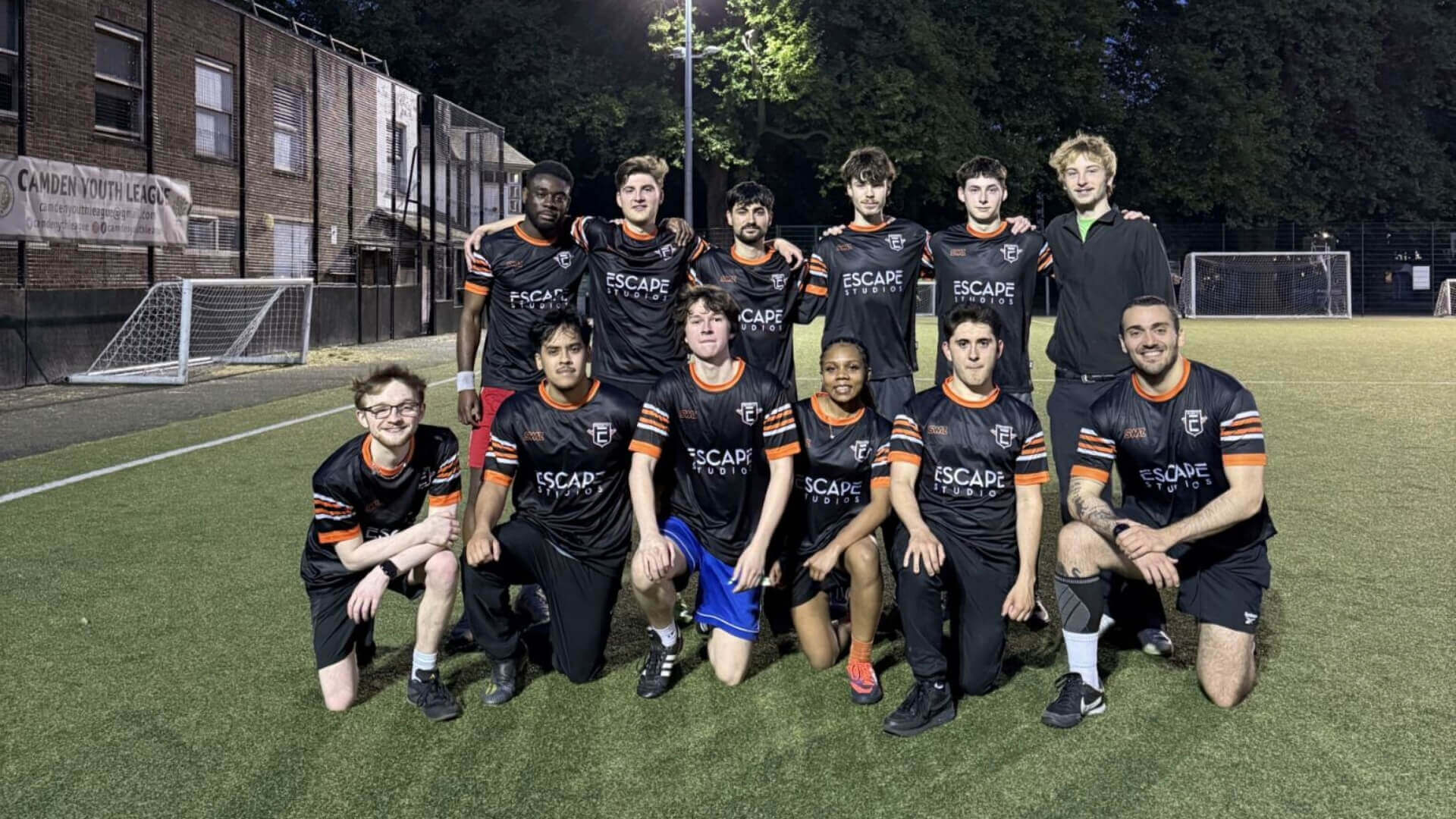 A group of students wearing football kit posing for a photo on a football pitch